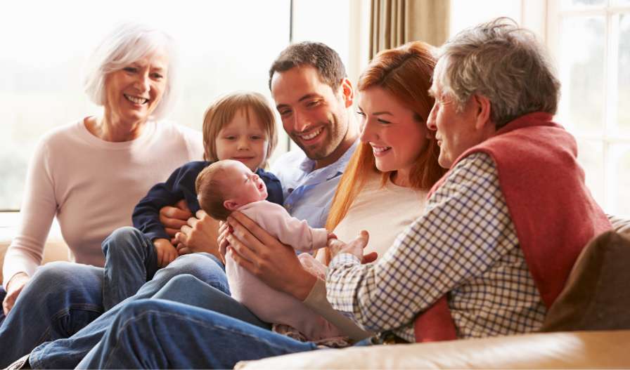 parents, grandparents, and sibling gather around their new baby