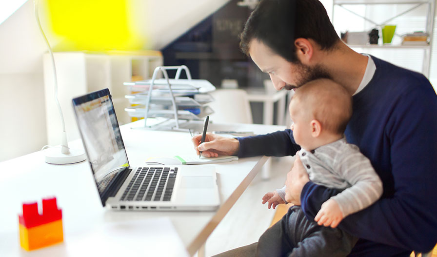 papá que trabaja en su computadora portátil con su bebé en el regazo