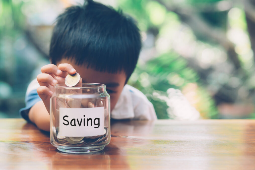 Kid puts money in a saving jar.