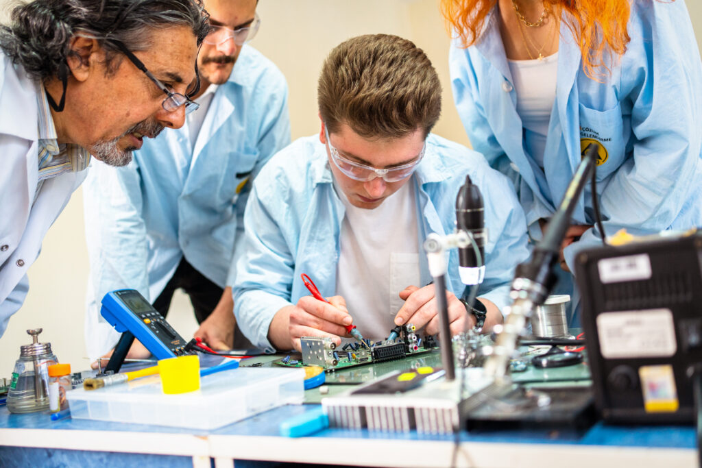 Group of young people work in technical vocational training with their teacher.