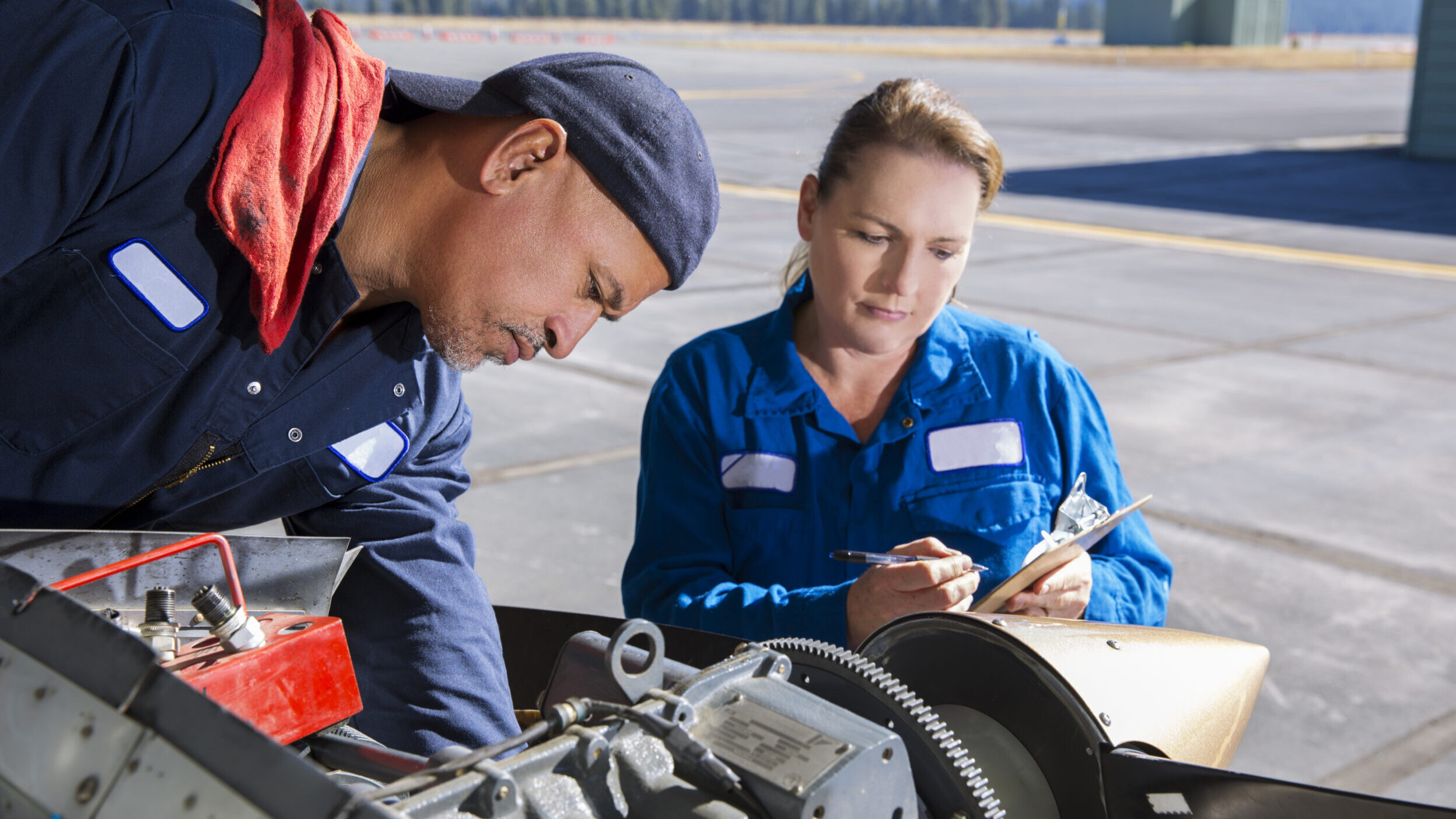 Female and male airplain mechanics working on a small plane at the airport.